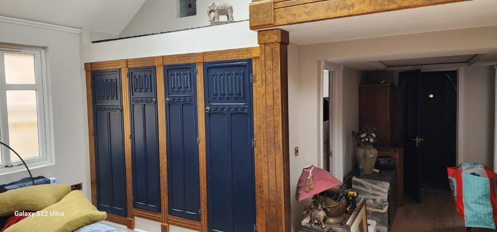 Large handmade wardrobe under an elevated platform with an opening to other rooms on the right.