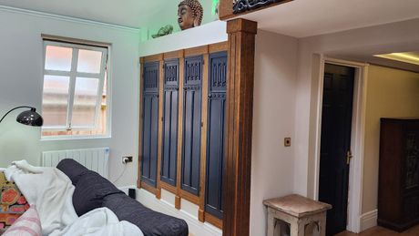 Large handmade wardrobe under an elevated platform with an opening to other rooms on the right.