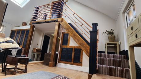Blue skirting board with a staircase covered in lined coloured carpet with copper handrails, with view of the view of the neighbouring room.